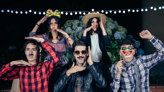 Friends posing for a photo in Halloween costumes with sunglasses, bows, hats and fake mustaches 