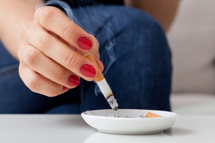 A woman who is trying to conceive, putting out a cigarette in a white ash-tray