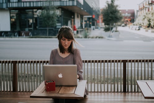 A woman sitting and using her laptop in an outdoor bar
