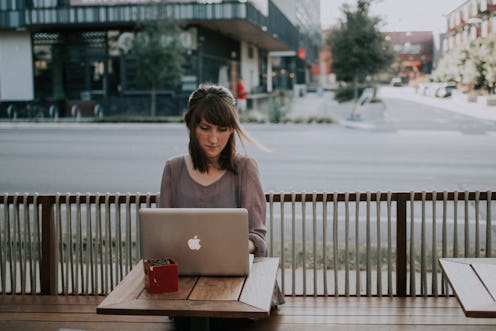 A woman sitting and using her laptop in an outdoor bar