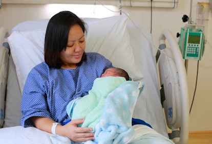 A mother sitting up in a hospital bed holding her newborn baby