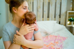 Woman holding her newborn baby to her chest and kissing its head
