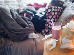 A woman who caught the flu, sleeping in her bed with a drink, napkins, and a body thermometer
