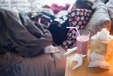 A woman who caught the flu, sleeping in her bed with a drink, napkins, and a body thermometer