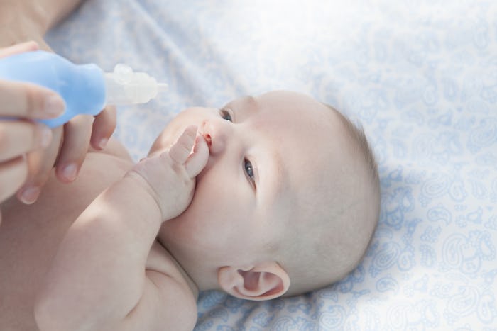 A parent using a Nasal aspirator to suck out her baby's snot 