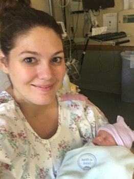 Maranda Davis sitting up and smiling while holding her newborn baby