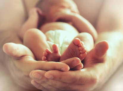 Mothers hands holding her baby in her arms 