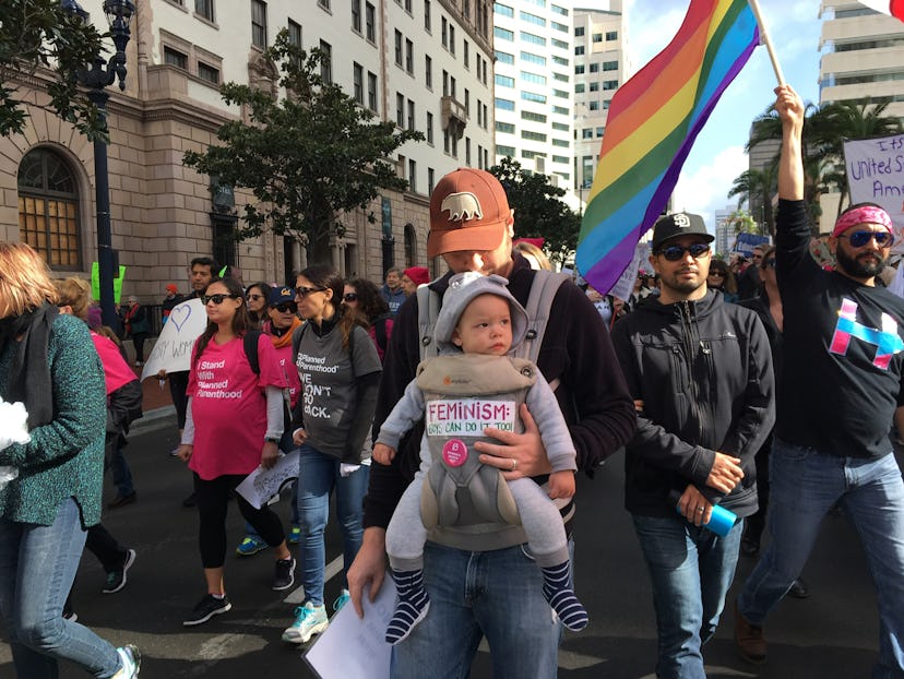 A father walking with his son in a baby carrier at the Women's March
