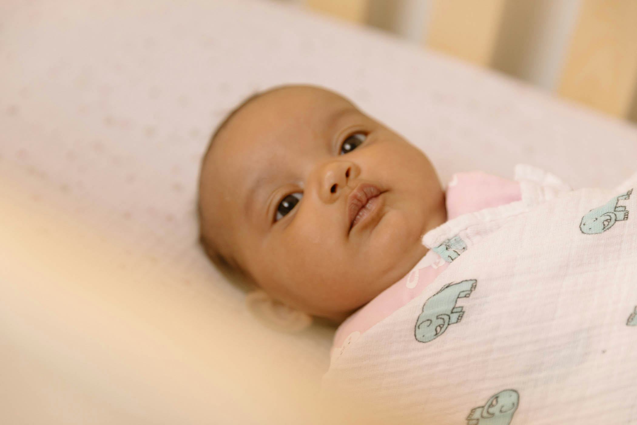 Swaddled baby with strep throat lying in her bed