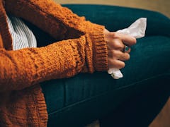 A woman in a mustard sweater holding a napkin on her lap, because she caught the flu