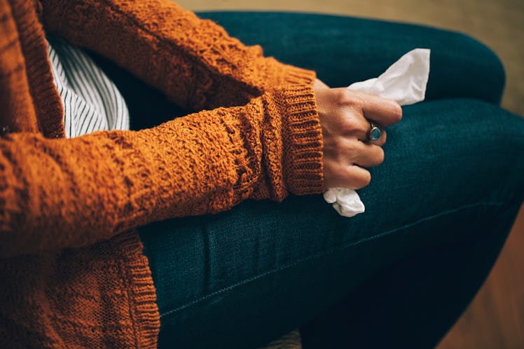 A woman in a mustard sweater holding a napkin on her lap, because she caught the flu