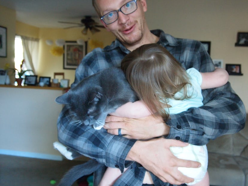 Gemma Hartley’s husband holding a toddler daughter and a grey Russian cat in his arms.