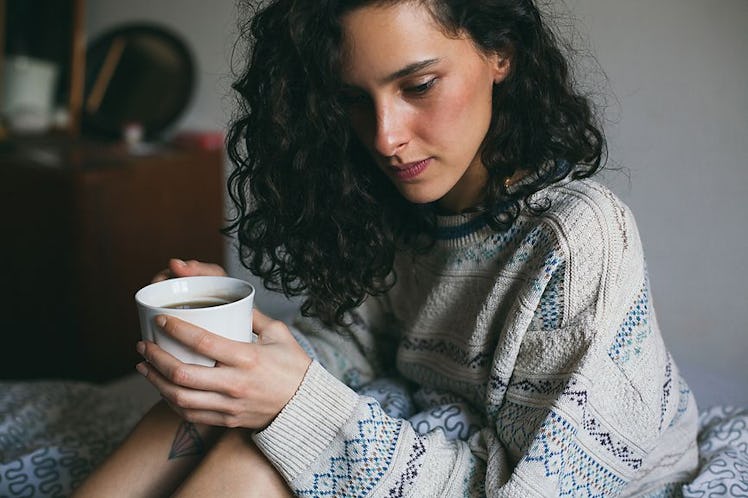 A young woman drinking tea while having a flu