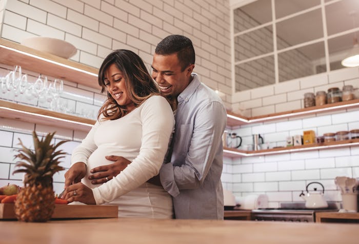 Pregnant woman and partner in kitchen preparing a snack
