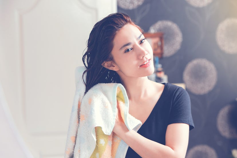 Brunette woman drying her hair and analyzing the changes in her hair's texture