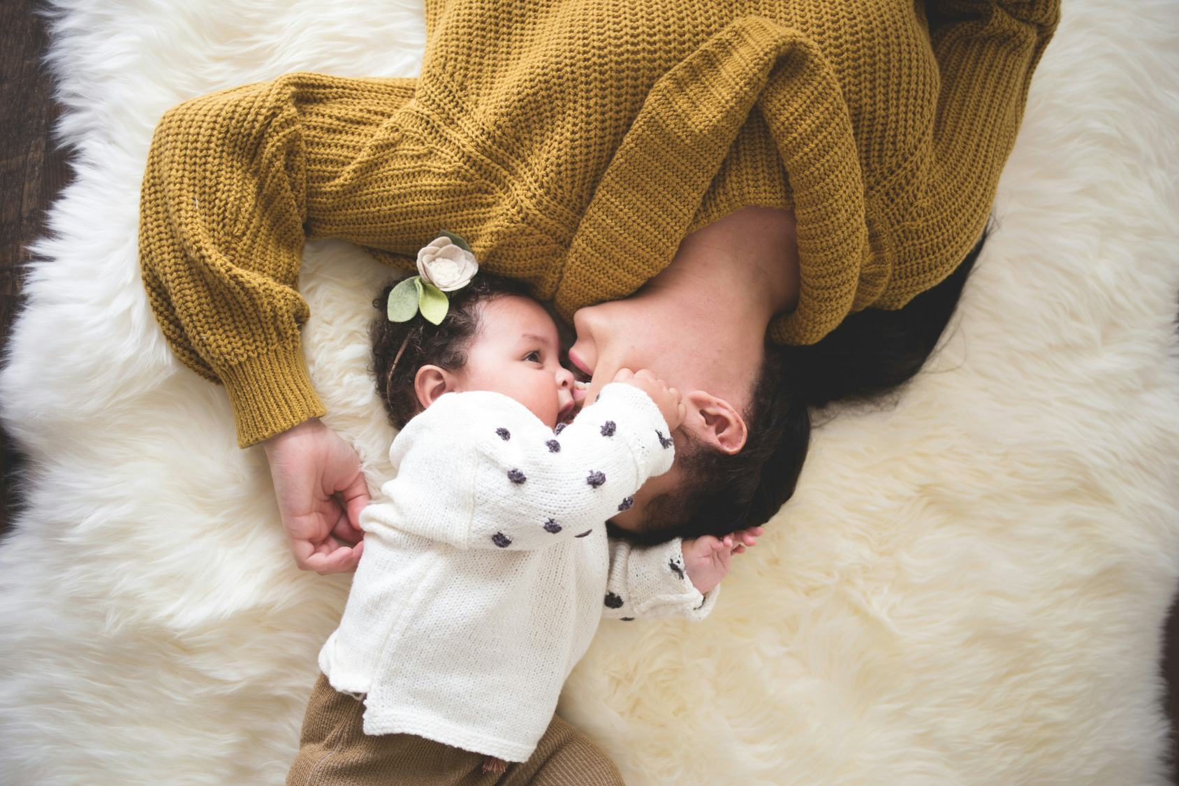 Millennial mom with postpartum depression cuddling with her baby on the bed