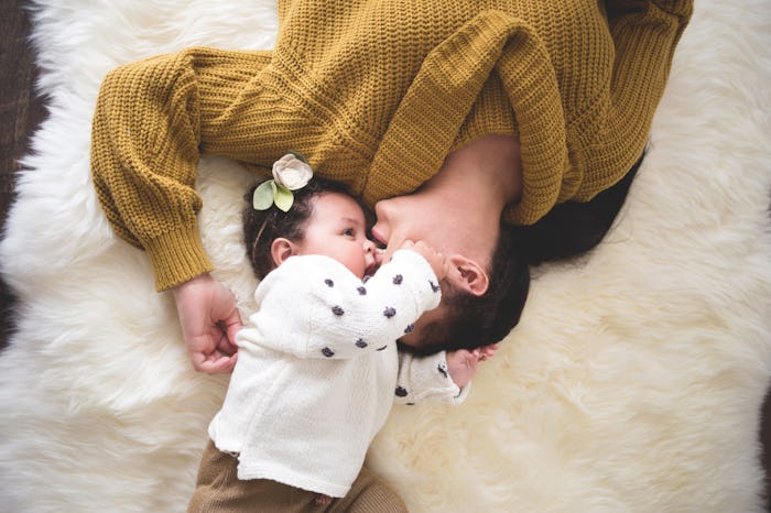 Millennial mom with postpartum depression cuddling with her baby on the bed