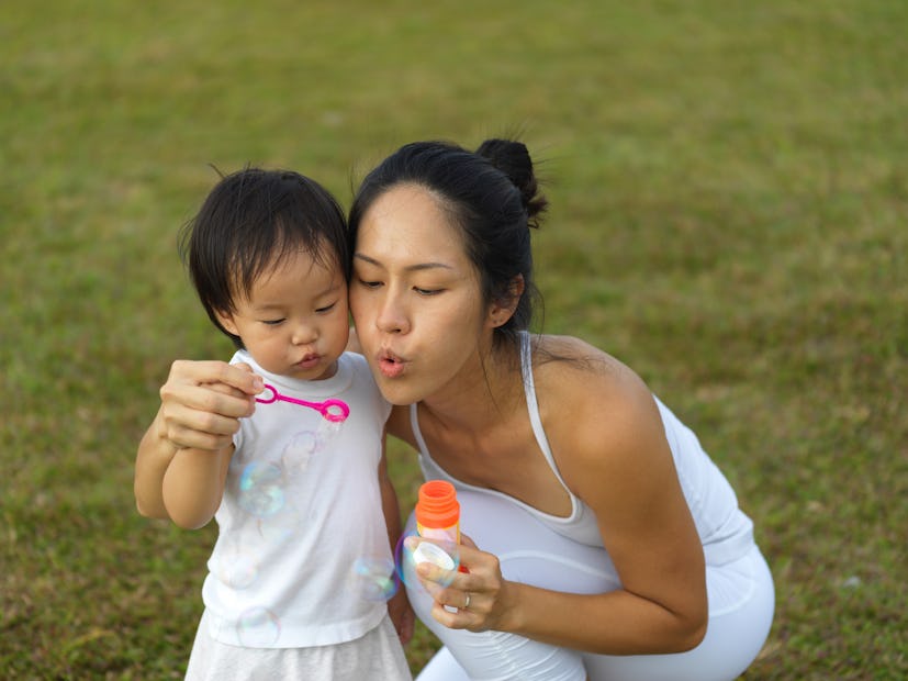 A mom and her baby blowing bubbles in the park