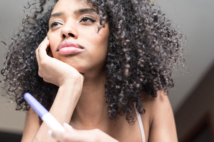 A woman holding a pregnancy test and thinking about how IUI goes down