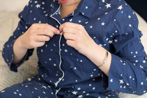 A woman in navy and white pajamas unbuttons her top to do a breast self-exam. What should breast can...