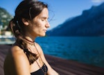 A woman with her eyed closed, doing yoga on the dock.