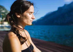 A woman with her eyed closed, doing yoga on the dock.
