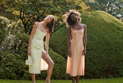 Two models wearing Markarian romantic dresses in yellow and peach posing in a garden
