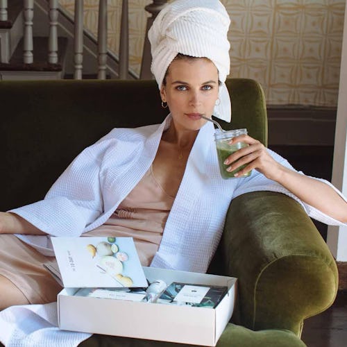 A woman wears a bathrobe and towel over her hair while using a 10-day fall detox products.