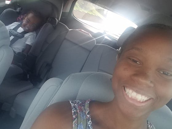 Rochaun Meadows-Fernandez smiling while taking a car selfie with her son sitting in a car seat at th...
