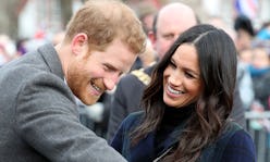 Meghan Markle and Prince Harry saying hello the a crowd while smiling at each other 