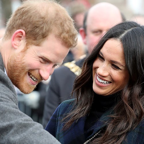 Meghan Markle and Prince Harry saying hello the a crowd while smiling at each other 