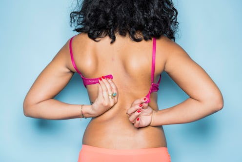 A woman experiencing unexpected signs of breast cancer having trouble closing her bra
