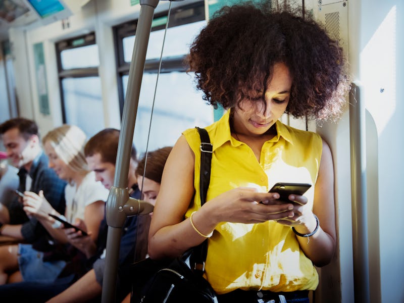A young woman is seen on a bus, holding her phone.