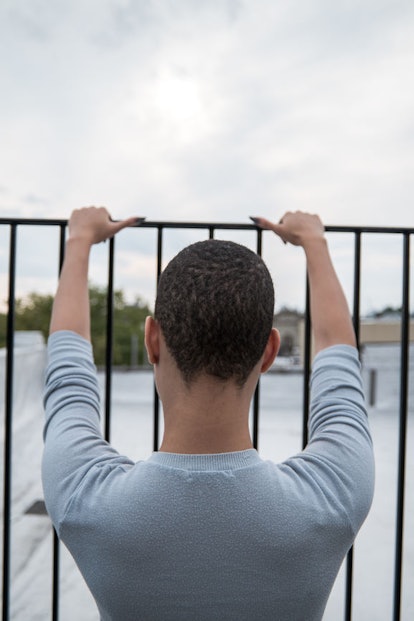 A boy standing leaned on a fence as it is a cage