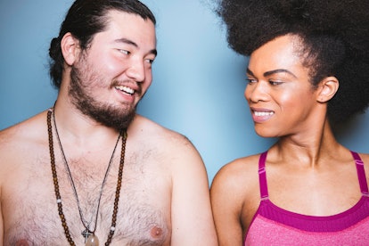A topless man and a woman in a pink bra looking at each other with a blue background