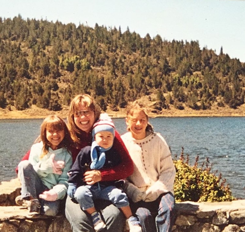 The author's sister, mother, brother, and the author posing for a photo next to a lake