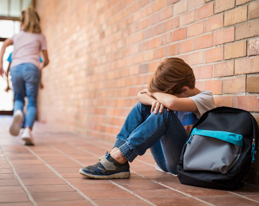 Bullied kid sitting in the school hall with his heads in his hands