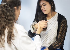 A curly-haired primary care doctor checking her patient's pulse