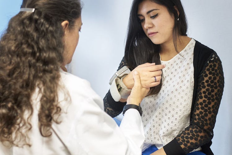 A curly-haired primary care doctor checking her patient's pulse