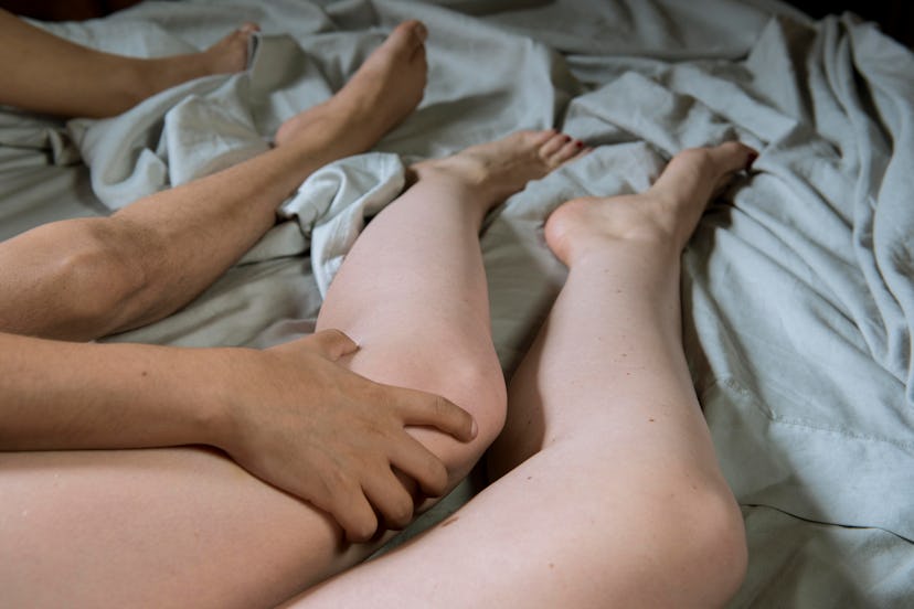 A man grabbing a woman's leg and his legs are next to hers as they're both lying 