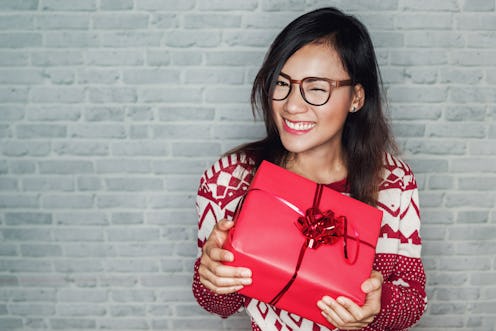 Black haired woman wearing sunglasses holding a wrapped gift