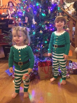 Jamie Kenney's kids wearing elf costumes while standing in front of a Christmas tree