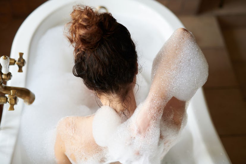 A woman washes and scrubs her back while in a bath tub to ease her depression