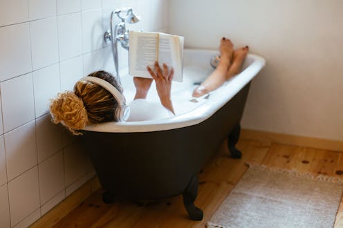 A woman listening music and reading a book while in a bath tub to ease her depression