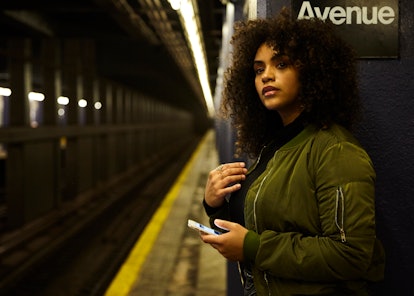 Young girl holding her phone while waiting for the subway