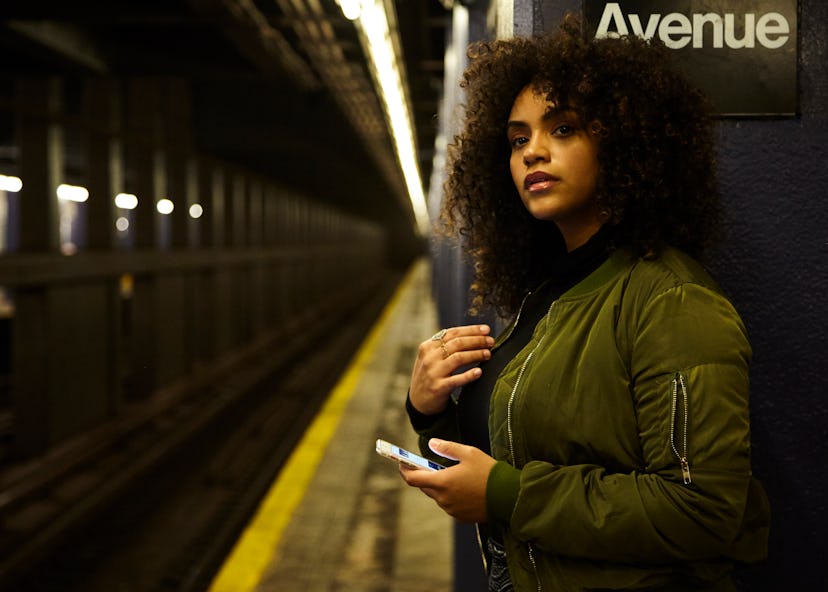 Young girl holding her phone while waiting for the subway