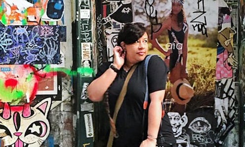 Stephanie Perez posing for a photo in front of a colorful graffiti wall