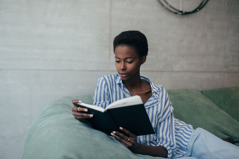 A young woman reading a book on the couch