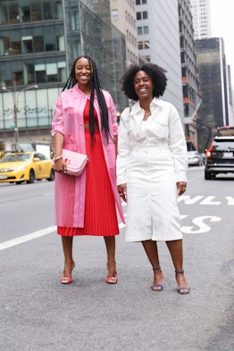 A woman wearing a white denim dress standing on the street next to her friend wearing bright colors