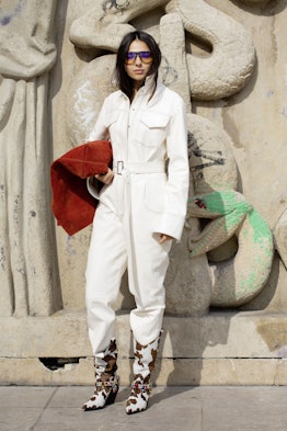 A woman wearing a boilersuit in an off-white hue paired with cowskin boots.